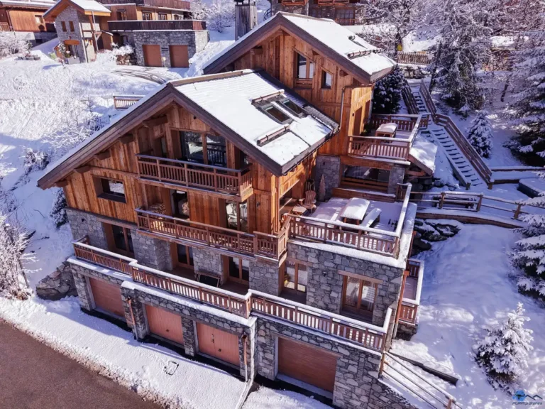 Location de chalet de luxe à Méribel 1 vue drone du chalet Etoile des Neiges à Méribel avec jacuzzi visible sur la terrasse extérieure enneigée. Location chalet luxe à Méribel