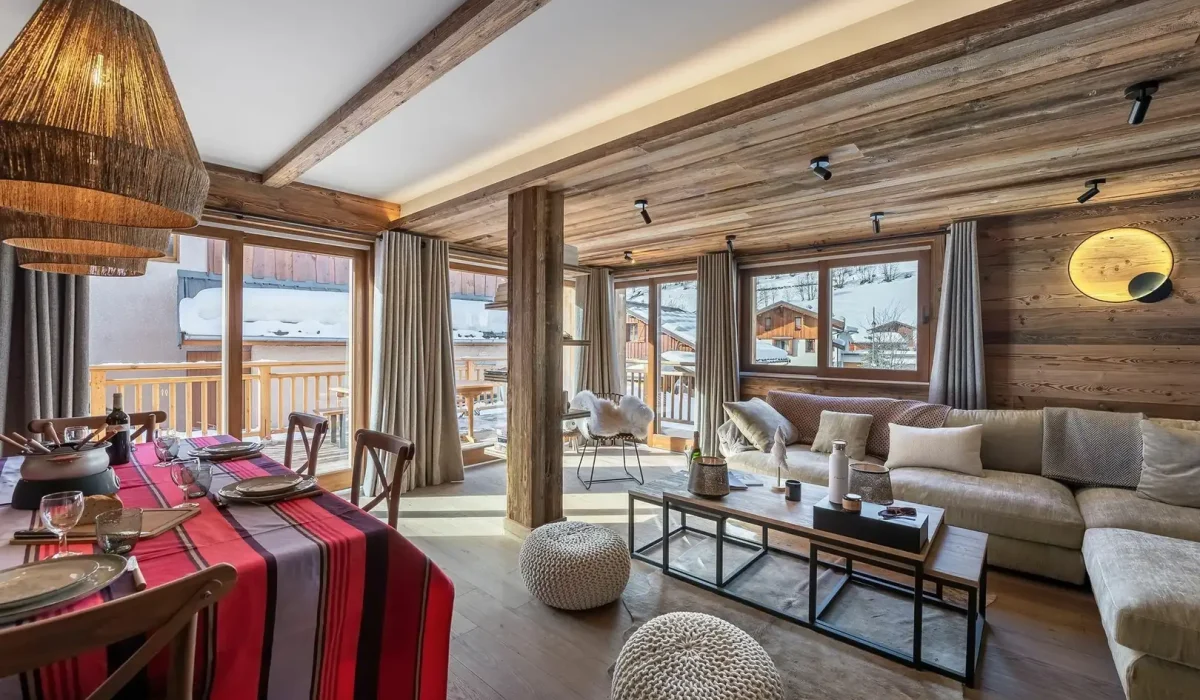 Dining area with a table laid for fondue and the lounge opening onto the terrace at Apartment Campanule in Saint-Martin-de-Belleville