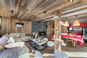 Lounge and dining room in reclaimed wood, with a stone fireplace and an open red kitchen at Apartment Campanule in Saint-Martin-de-Belleville