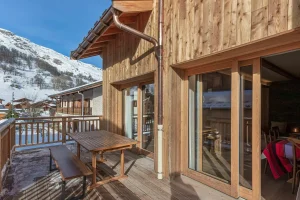 Timber terrace with an outdoor table and bench in front of the sliding windows at Apartment Campanule in Saint-Martin-de-Belleville