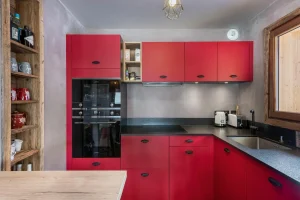 Equipped red kitchen with built-in ovens, an induction hob and a granite worktop at Apartment Campanule in Saint-Martin-de-Belleville