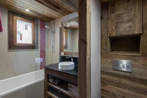 Bathroom with a bathtub, a round basin on a wooden unit and a wall-hung toilet at Apartment Campanule in Saint-Martin-de-Belleville