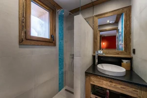 Shower room with beige tiles, a turquoise strip and a basin on a wooden unit at Apartment Campanule in Saint-Martin-de-Belleville