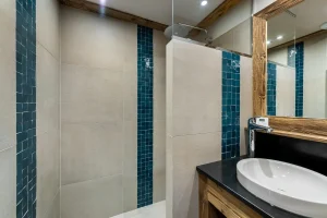 Shower room with a walk-in shower, a strip of blue tiles and a large mirror at Apartment Campanule in Saint-Martin-de-Belleville