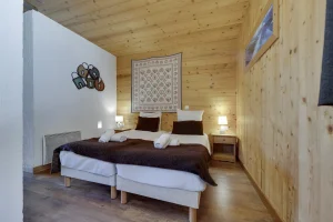 Twin bedroom with timber panelling and a wall hanging, at Apartment des Eucherts