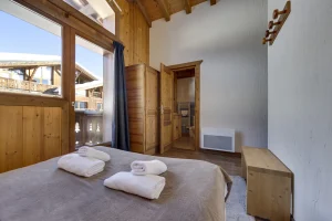 Double bedroom with folded towels on the bed and a balcony, at Apartment des Eucherts