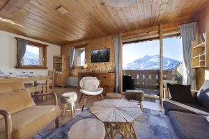 Lounge with sofas, a wooden coffee table and a glazed door opening onto the terrace and mountains, at Apartment des Eucherts