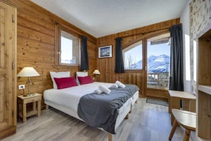 Bedroom with single beds, a grey throw and a window onto the mountain, at Apartment des Eucherts