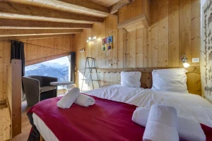 Attic double bedroom with a red bedspread and an armchair, at Apartment des Eucherts