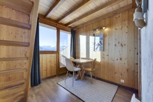 Desk nook with a table and chairs in a bedroom under the roof beams, at Apartment des Eucherts