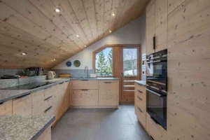 Equipped kitchen under a sloping timber ceiling, with a built-in oven and a glazed door, at Apartment Rhodos