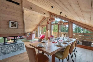 Dining room with a large timber table, a central fireplace and windows onto the balcony at Apartment Rhodos