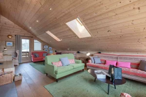Lounge under a sloping timber ceiling with roof windows, a green sofa and a pink striped sofa at Apartment Rhodos