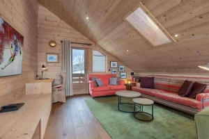 Lounge corner with a red sofa, round coffee tables and a skier poster at Apartment Rhodos