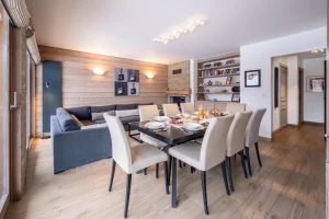 Dining room with a laid table and a lounge with a corner sofa at Chalet Alisier in Méribel Village