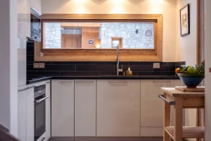 Equipped kitchen with a window onto the dining room at Chalet Alisier in Méribel Village