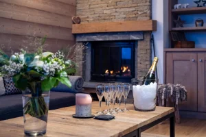 Lounge corner with a stone fireplace and a wooden coffee table at Chalet Alisier in Méribel Village