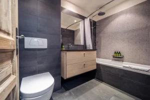 Bathroom with a bathtub, a wooden vanity unit and grey tiles at Chalet Alisier in Méribel Village