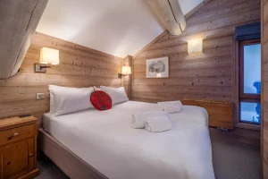Double bedroom with a white bed and a window at Chalet Alisier in Méribel Village