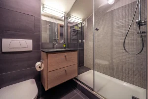 Shower room with a glass shower, a washbasin and a wooden vanity unit at Chalet Alisier in Méribel Village