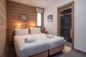 Bedroom with two single beds and an en-suite bathroom at Chalet Alisier in Méribel Village