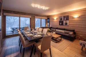 Bright lounge and dining area with large windows onto the terrace at Chalet Alisier in Méribel Village