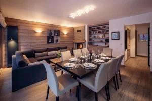 Dining room and lounge with a fireplace and a bookcase at Chalet Alisier in Méribel Village