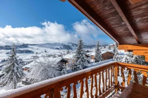 Balcony with a cut-out timber balustrade and a view of snow-covered fir trees at Chalet Arnica in Les Saisies