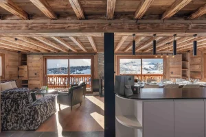 Lounge and open kitchen seen from the dining room, with a view onto the balcony at Chalet Arnica in Les Saisies