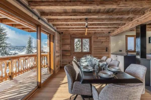 Dining room with a laid table and a large window onto the balcony at Chalet Arnica in Les Saisies