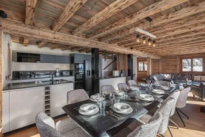 Large dining table with chairs and the kitchen beyond at Chalet Arnica in Les Saisies