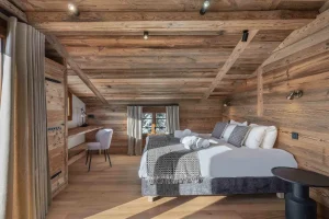 Reclaimed-wood bedroom with a bed, a desk and curtains at Chalet Arnica in Les Saisies