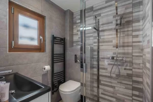 Shower room with a black washbasin, a wall-hung toilet and a walk-in shower at Chalet Arnica in Les Saisies
