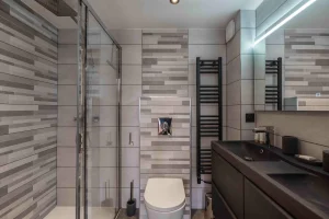 Shower room with a black double washbasin and a towel radiator at Chalet Arnica in Les Saisies