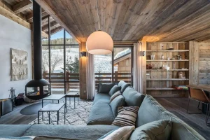 Lounge with a large corner sofa, a suspended fireplace and picture windows onto the balcony at Chalet Bouleau in Méribel