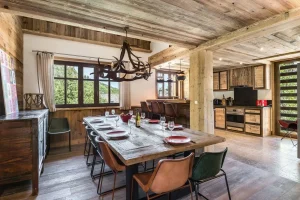 Dining room with a large reclaimed-wood table and an antler chandelier at Chalet Bouleau in Méribel