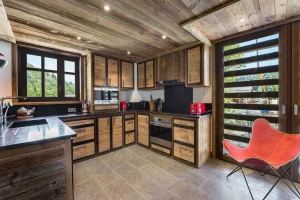 Reclaimed-wood kitchen with a black worktop, an oven and a French door at Chalet Bouleau in Méribel