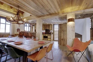 Dining room with a laid table and open kitchen under light timber beams at Chalet Bouleau in Méribel