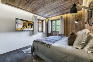 Bedroom with a double bed, a wall-mounted TV and reclaimed-wood panelling at Chalet Bouleau in Méribel