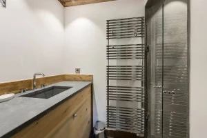 Shower room with a stone basin, a towel radiator and a glass shower at Chalet Bouleau in Méribel