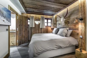 Double bedroom with a reclaimed-wood headboard, a bull's head and a TV at Chalet Bouleau in Méribel