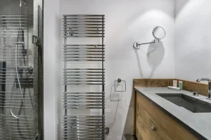 Shower room with a towel radiator, a magnifying mirror and a stone basin at Chalet Bouleau in Méribel