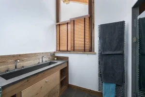 Bathroom with a double stone washbasin on a wooden unit and a window at Chalet Bouleau in Méribel