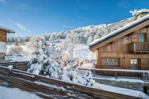 View from the balcony over the snowy slope and a neighbouring chalet at Chalet Bouleau in Méribel