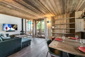 Lounge with a sofa, a TV and a fireplace, with a laid table in the foreground at Chalet Bouleau in Méribel