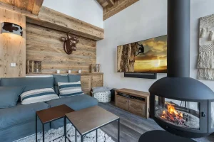 Black suspended fireplace facing the TV and the reclaimed-wood wall at Chalet Bouleau in Méribel