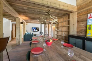 Long reclaimed-wood table laid for twelve under an antler chandelier at Chalet Bouleau in Méribel