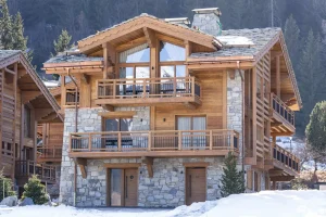 Timber and stone chalet façade with balconies in the snow in Courchevel Le Praz