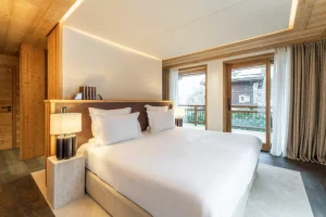 Master suite with a king-size bed, a picture window and balcony access at Chalet Brigues in Courchevel Le Praz
