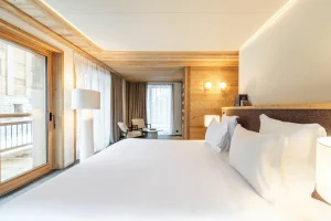 White double bed in the master suite with a headboard and a window onto the mountains at Chalet Brigues in Courchevel Le Praz